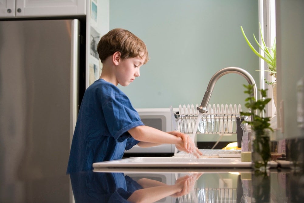 young boy washes hands at sink to prevent respiratory illnesses